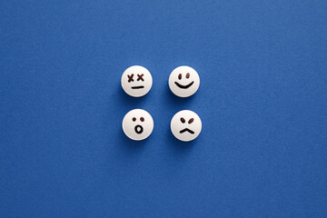 Pills with drawn faces on blue background