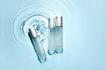 Bottles of cosmetic products in water on blue background