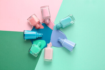 Overturned bottles of nail polishes on color background