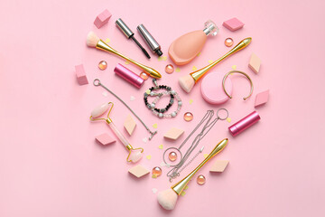 Heart made of accessories and cosmetics on color background