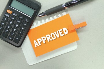 calculator, pen and blank paper with the word Approved