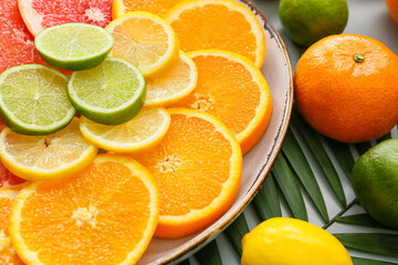 Plate of different citrus fruits on grey background, closeup