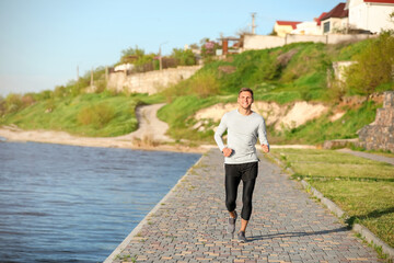 Sporty young man jogging near river