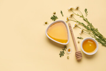 Composition with bowls of sweet honey and chamomile flowers on color background