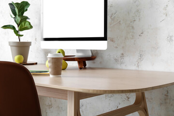 Table with brown chair and computer near light wall