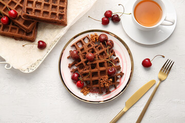Plate with delicious Chocolate Belgian Waffles, cherry, walnut and cup of tea on white background