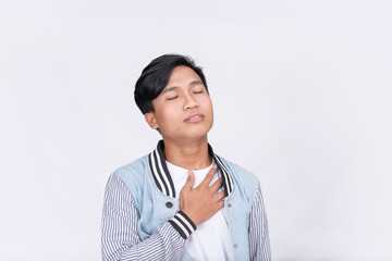 A young Filipino breaths a sigh of relief. Hands on chest and eyes closed. Isolated on white...