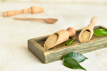 Wooden board and scoops with hojicha powder on light background