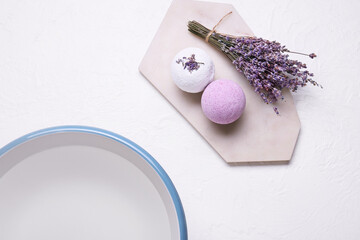Obraz na płótnie Canvas Bath bombs, lavender flowers and bowl with water on light background, closeup