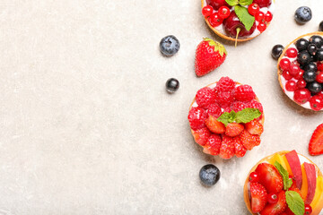 Composition with tasty berry tartlets on grunge background