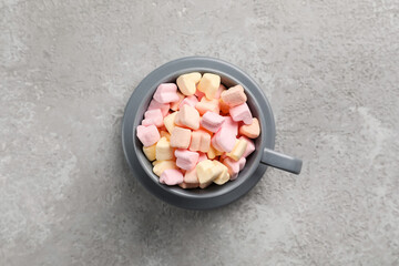 Cup with tasty marshmallows on grey background