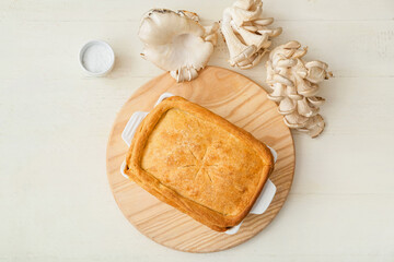 Baking dish with tasty mushroom pot pie on white wooden background