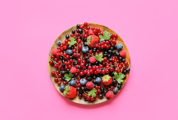 Plate with different ripe berries on color background