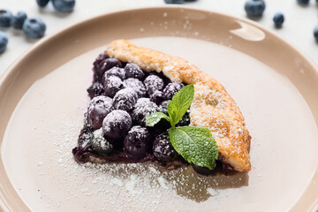 Plate with piece of tasty blueberry galette on table, closeup