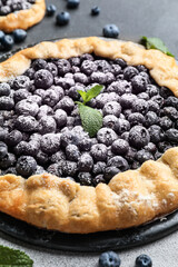 Plate with tasty blueberry galette on dark background, closeup