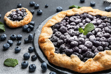 Plate with tasty blueberry galettes on dark background, closeup