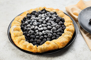 Plate with tasty blueberry galette on light background, closeup
