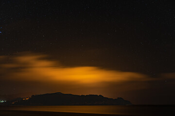 Fototapeta na wymiar night landscape of star sky over the island, from the beach