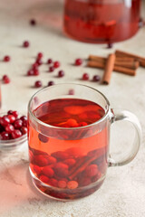 Glass cup of delicious cranberry tea on light background, closeup