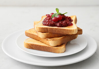 Plate with toasts and cranberry jam on light background, closeup