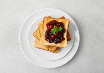 Plate with toasts and cranberry jam on light background