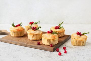 Board with tasty mince pies on light background