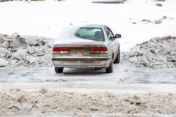a frozen old car covered with snow interferes with the cleaning of the parking lot from snow and...