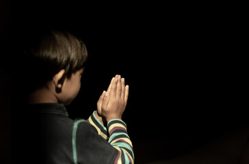 Obraz premium Little boy praying to God in dark background