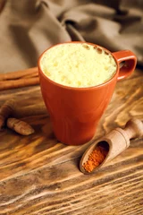 Fotobehang Cup of tasty latte and scoop with turmeric powder on wooden background © Pixel-Shot