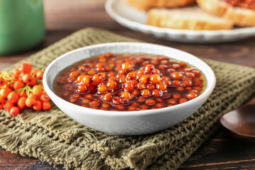 Bowl with sweet rowan jam on wooden background, closeup