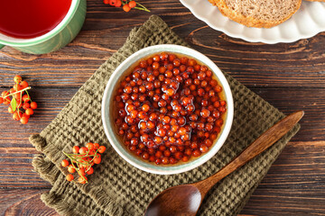 Bowl with sweet rowan jam on wooden background