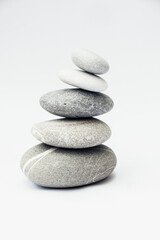 Stone cairn on light background, stones tower, simple poise stones. Purity harmony and Balance Concept. Vertical photo.