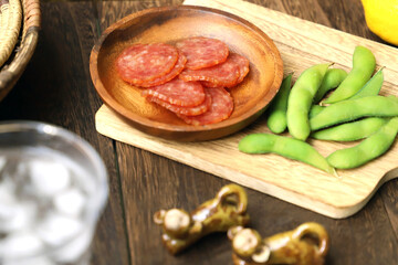 グラスに注がれた冷たく冷えたハイボールとサラミと枝豆のおつまみ