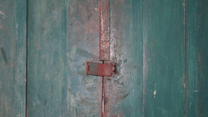 Architectural vintage background - old rusty metal padlock hanging on the wooden textured door. Focus at the padlock. 