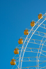 Close view of a ferris wheel, under blue sky.