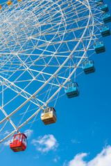 Close view of a ferris wheel, under blue sky.