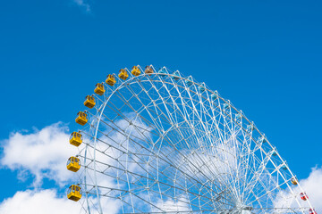 Close view of a ferris wheel, under blue sky.