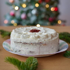 White cake on table with Christmas tree in background