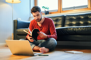 Male student learning at home browsing notebook