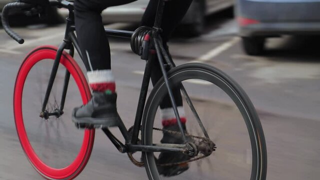 Professional cyclist rides fixed gear bike with red front wheel on an empty road