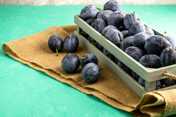 freshly picked ripe plum in a vintage box on a piece of burlap several plums lie next to each other...