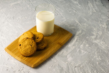 oatmeal cookies and a glass of milk on a wooden cutting board on the table