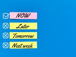 Words now, later, tomorrow and next week on paper strip against blue background.