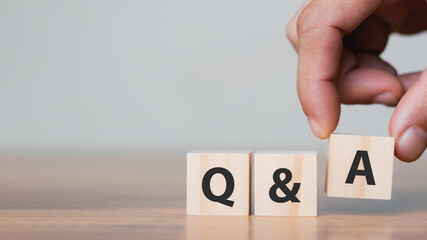 Hand holding Q and A words with wooden cube blocks , answers, ask questions, information,FAQ.