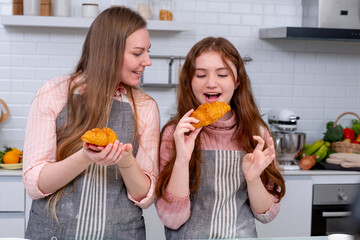 Caucasian mother with her daughter help to cook bakery together in kitchen and look happy with show to camera.