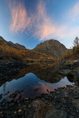 Reflection of mountains and clouds illuminated by a red sunset in a mountain lake