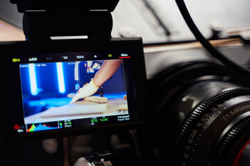 display of professional photo video camera.on the screen a man's hand in a glove holds a tool