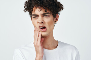 guy in white t-shirt with curly hair pain in the teeth health problems