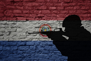Soldier silhouette on the old brick wall with flag of paraguay country.