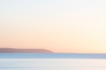Beautiful sunrise over Pentewan Sands in Cornwall with pastel sky and long exposure ocean